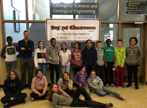 BCK students sitting in front of Beyond Classrooms Kingston sign at the Miller Museum of Geology.